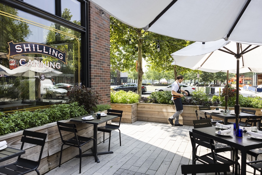 outdoor patio with umbrellas and dining setup, surrounded by herb gardens