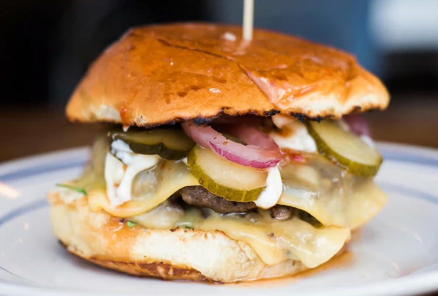 close up of burger with pickles onions and cheese