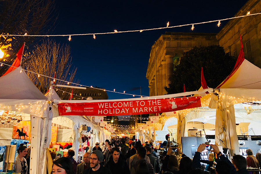 Photo of Downtown Holiday Market at night with string lights strung above the market tents 