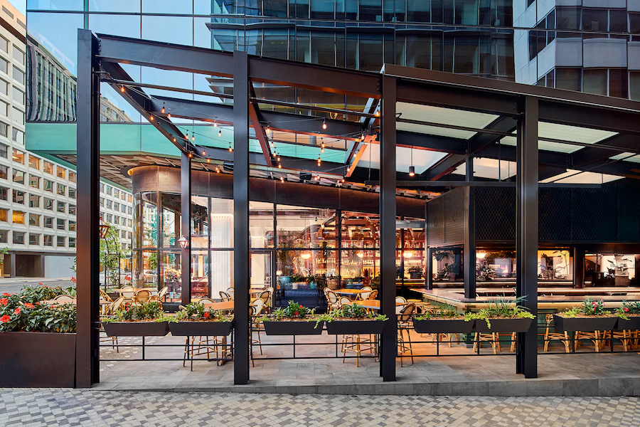 modern outdoor patio dining with plants, covering, and mirrored skyscraper behind