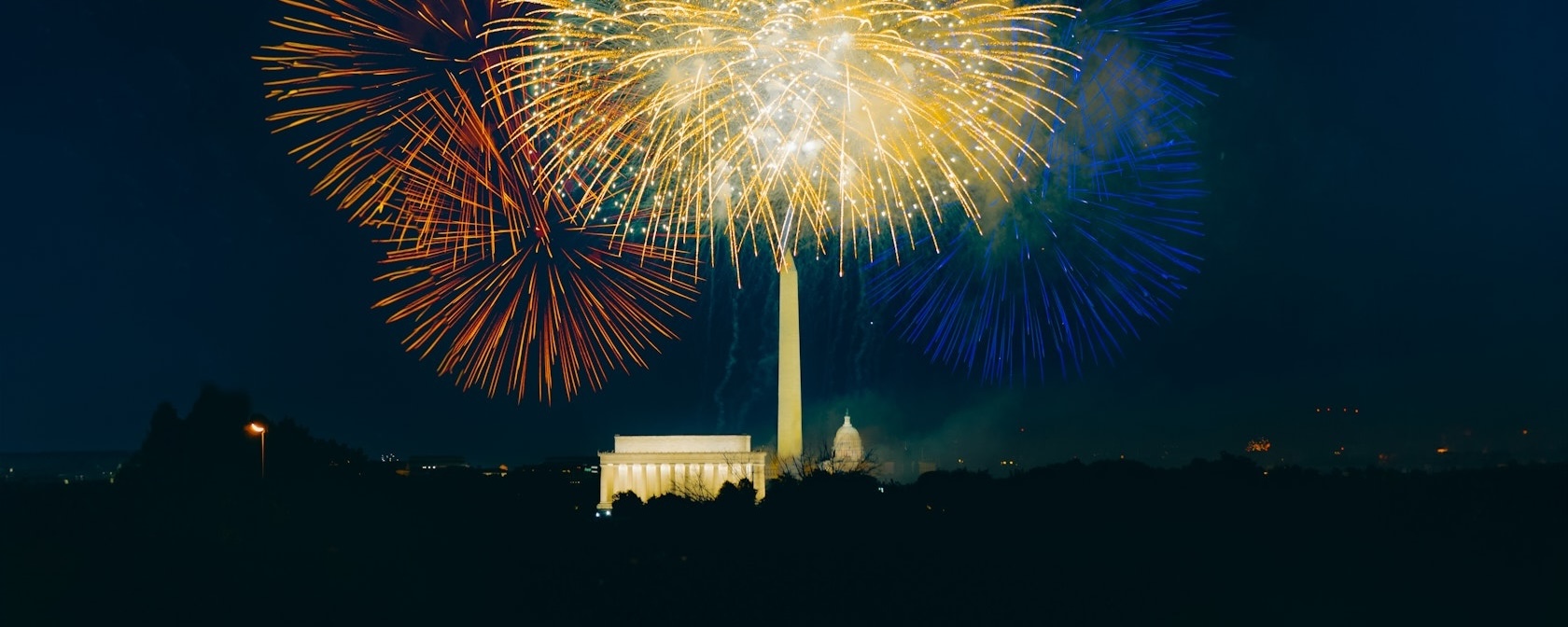 Colorful fireworks light up the night sky over the Washington Monument, Lincoln Memorial, and U.S. Capitol in Washington, DC, during a Fourth of July celebration.