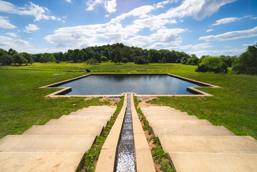 Symmetrical stone steps lead to a large reflecting pool surrounded by open grassy fields at the National Arboretum.