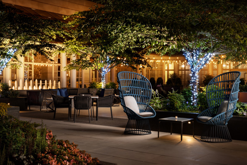 outdoor patio at night with big wicker black chairs and string lights