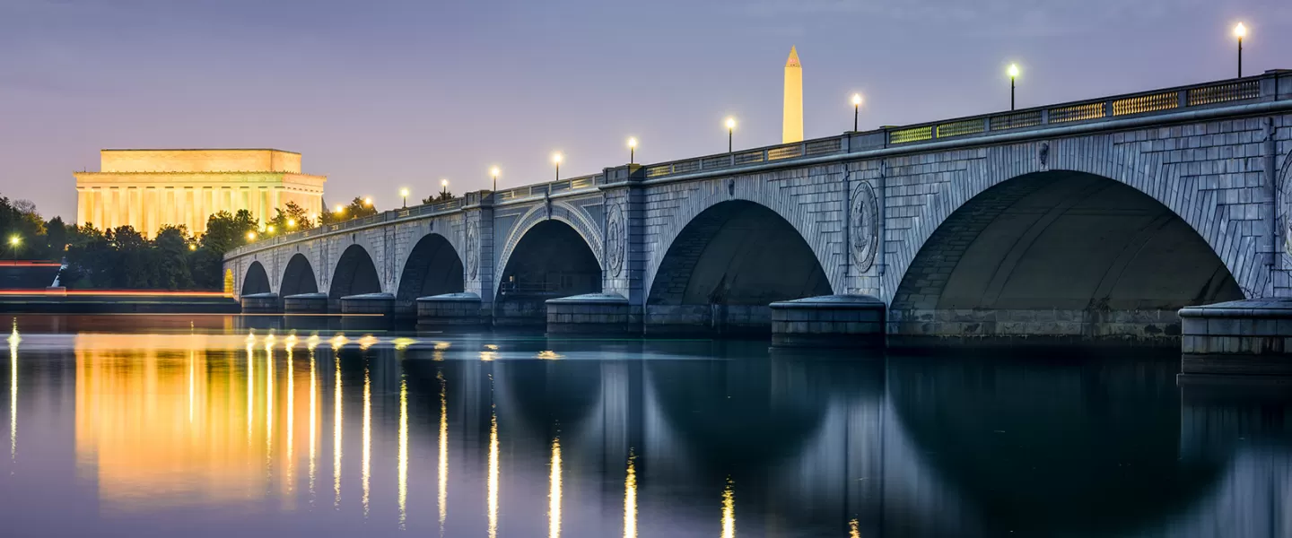 Arlington Bridge lit up at night with DC Skyline featuring Lincoln Memorial and Washington Monument