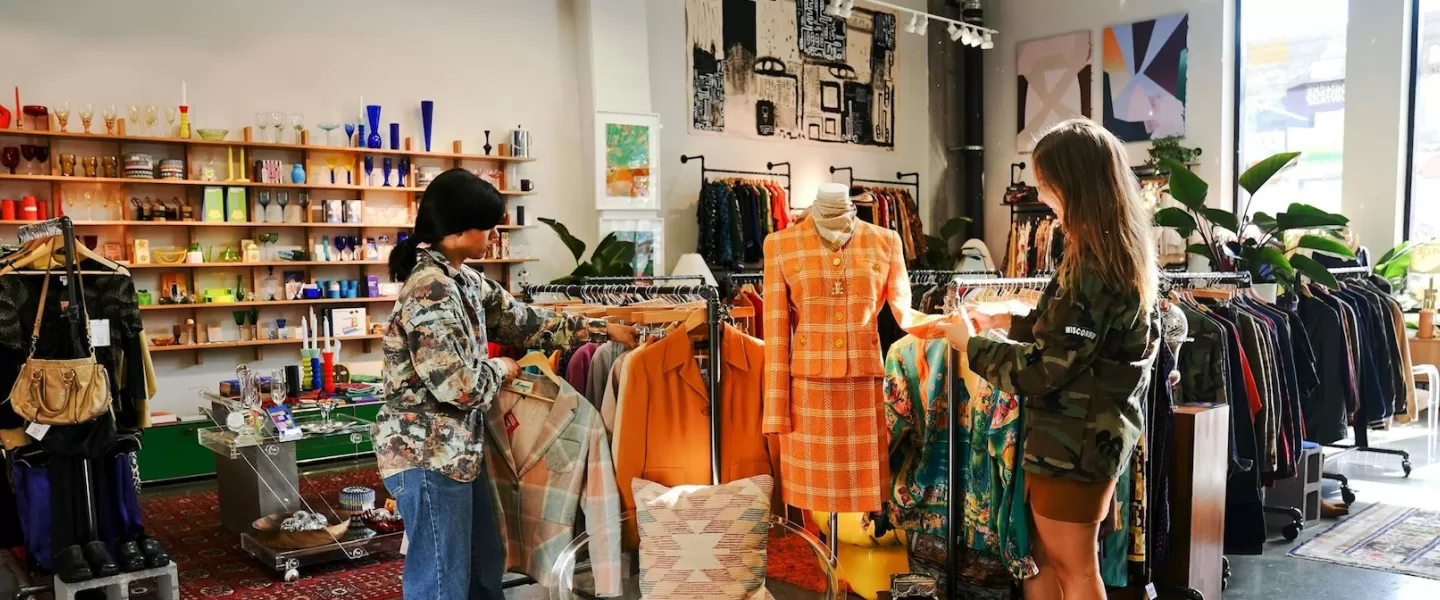 Two customers explore a well-curated vintage shop filled with unique fashion and home decor items.