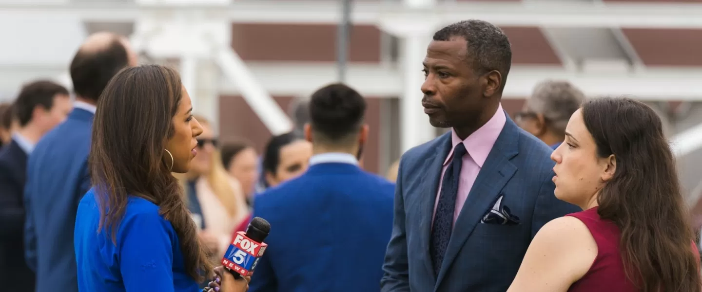 A reporter interviews a man in a suit at a press event. 