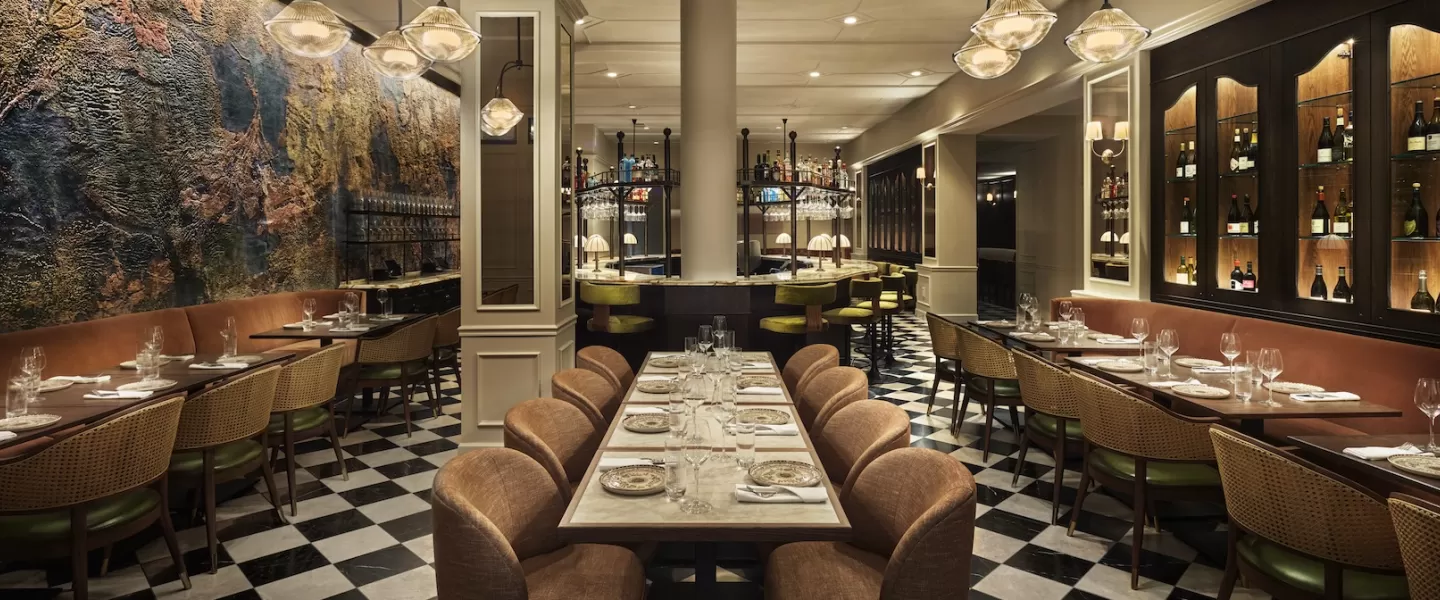 Elegant restaurant interior at Sixty DC featuring warm lighting, modern decor and a central bar with high stools.