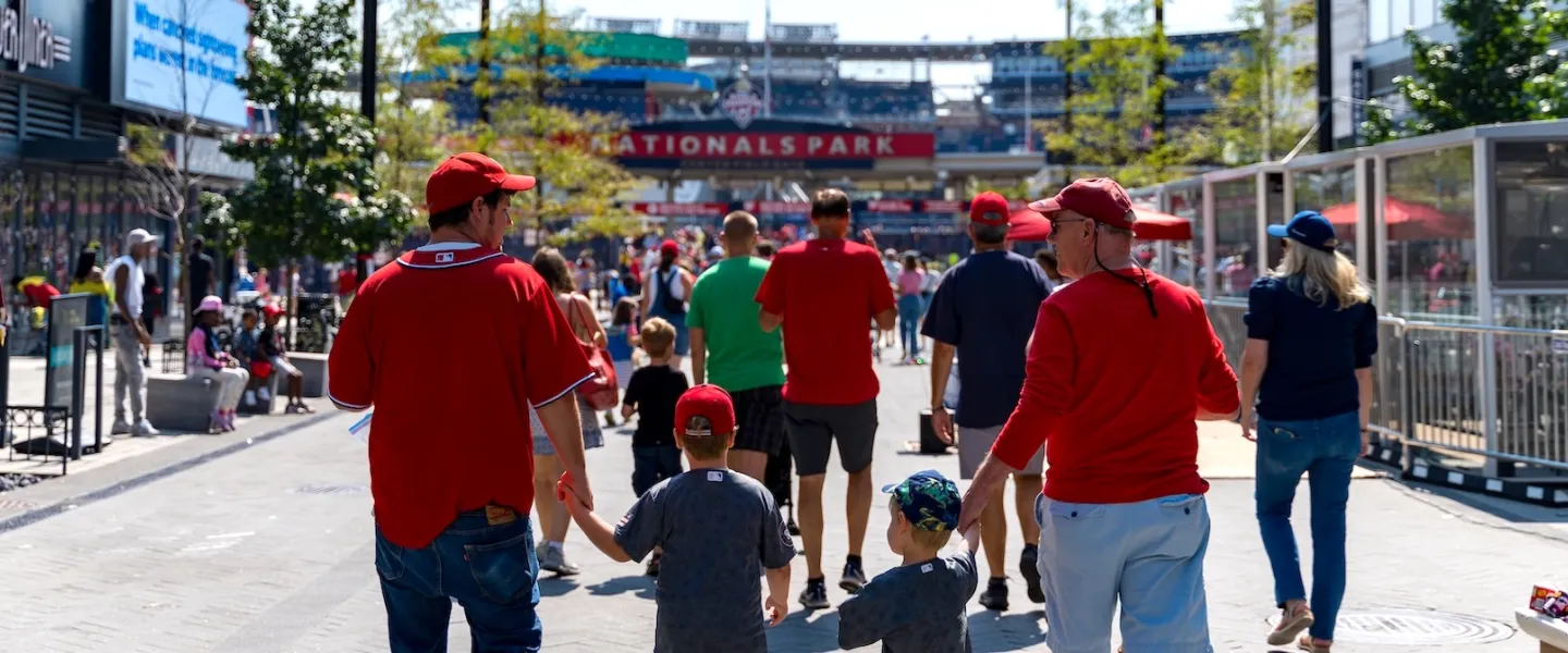 Families in red jerseys walking toward Nationals Park for a baseball game.