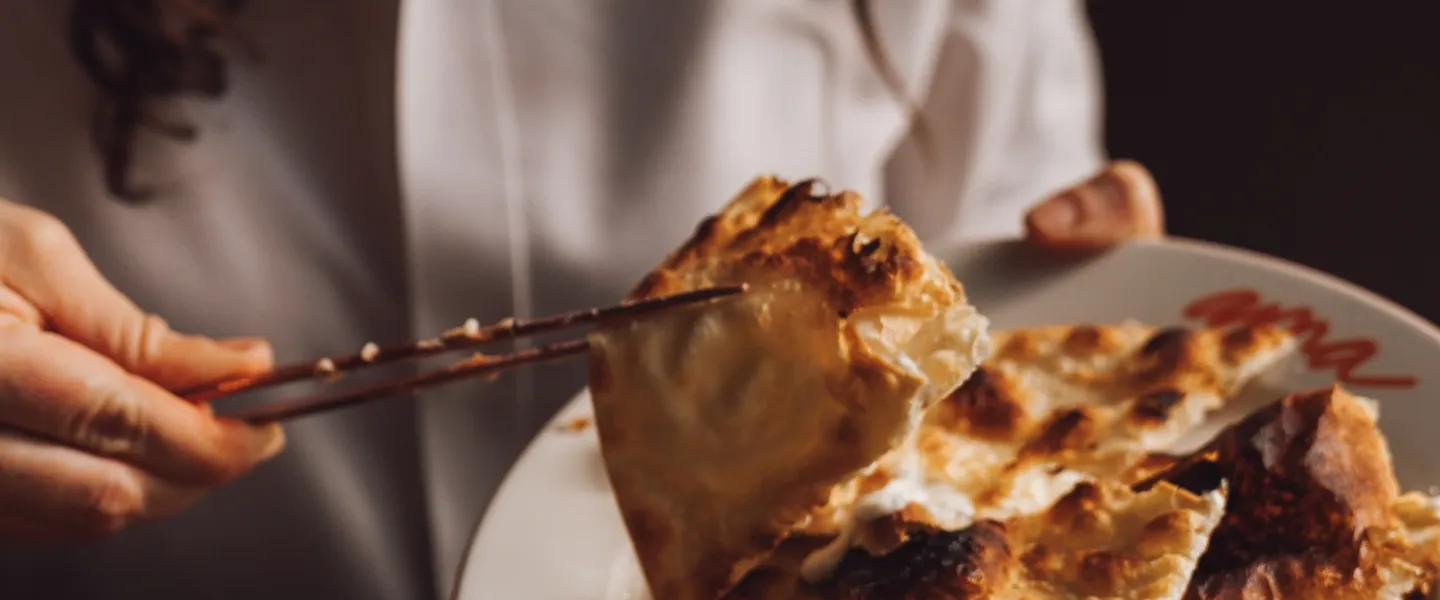 A hand uses chopsticks to lift some crispy, oven-fired bread off of a plate.