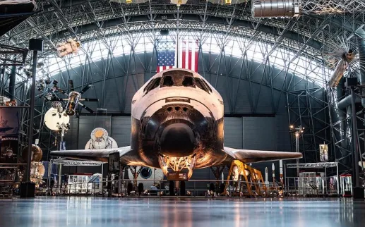 The Space Shuttle Discovery displayed inside the Smithsonian’s Steven F. Udvar-Hazy Center with spacecraft exhibits surrounding it.
