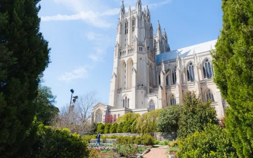 The towers of Washington National Cathedral rise above lush gardens on a bright spring day.
