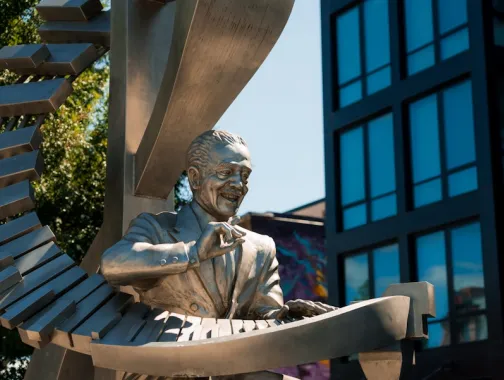 A silver-toned statue of Duke Ellington playing a grand, spiral-shaped piano stands along U Street.