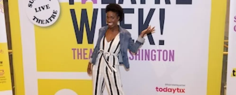 Woman posing in front of a Theatre Week banner.