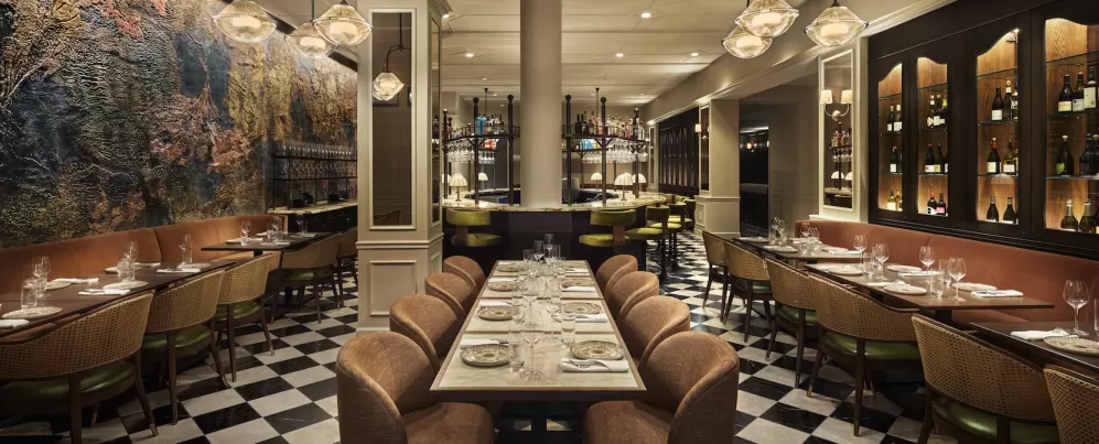 Elegant restaurant interior at Sixty DC featuring warm lighting, modern decor and a central bar with high stools.